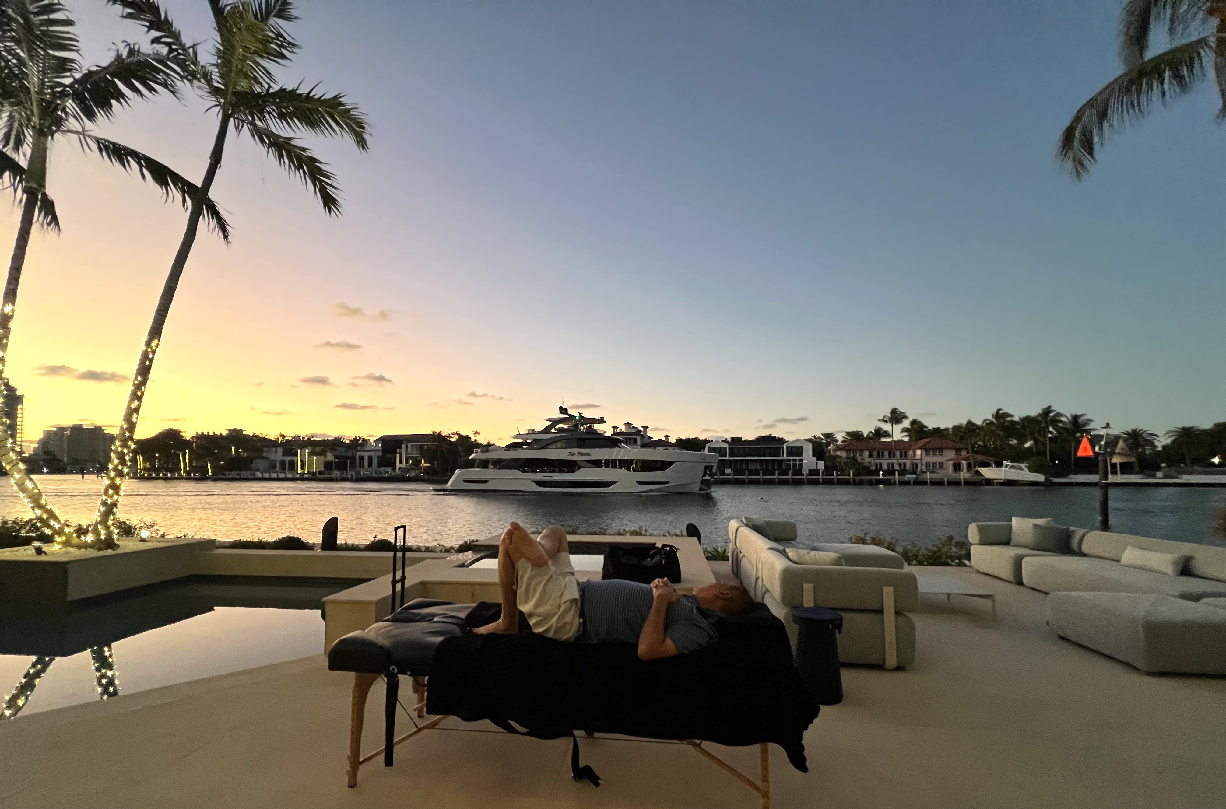 Client relaxing on a stretching table overlooking a Fort Lauderdale waterway at sunset