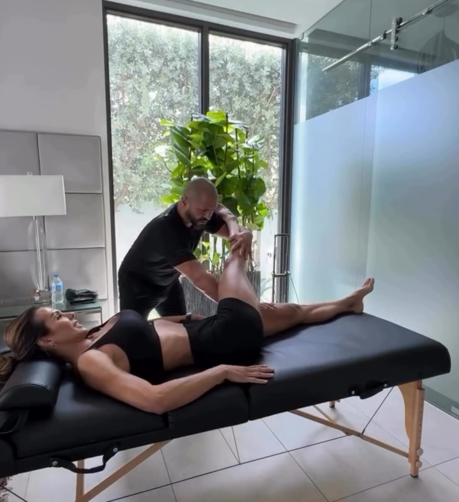 Roberto performing assisted stretching on a female client in a modern indoor setting
